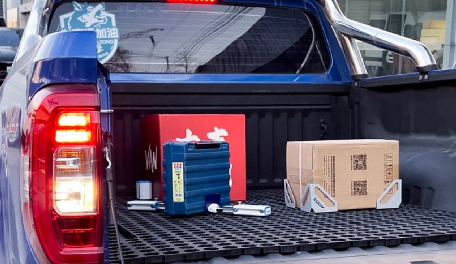 Modular cabin system in a pickup truck bed holding a tool case, cartons and containers